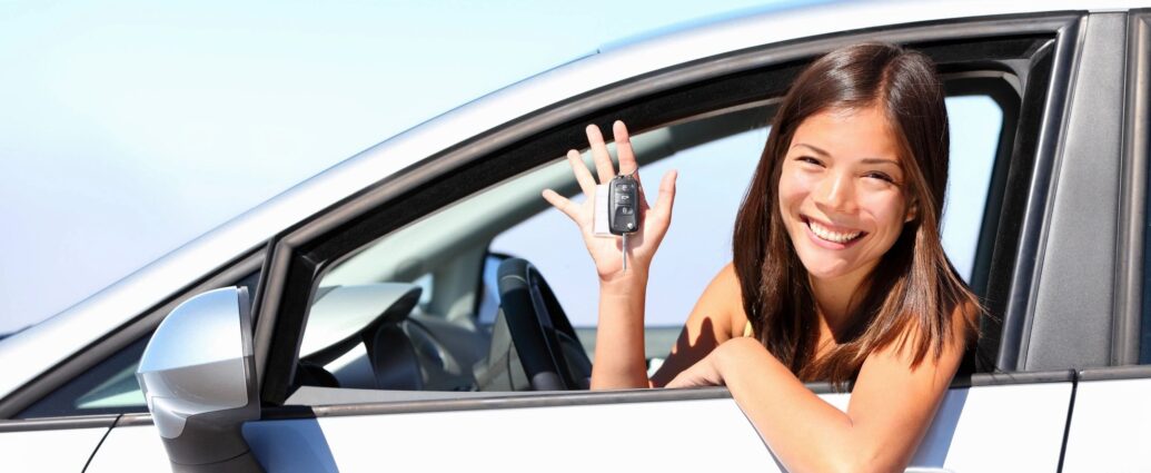 Young woman in driver seat of car showing off keys