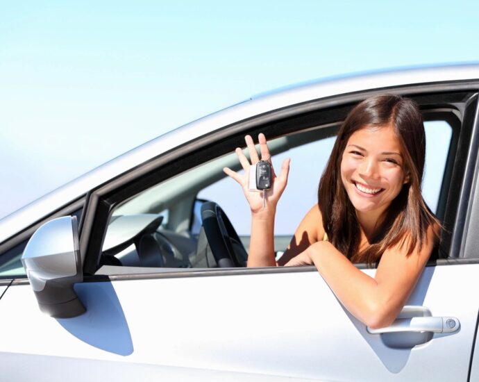 Young woman in driver seat of car showing off keys